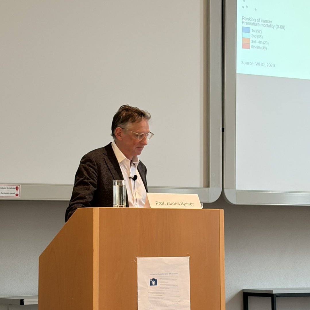 Prof. James Spicer speaking at a podium during a scientific conference presentation.