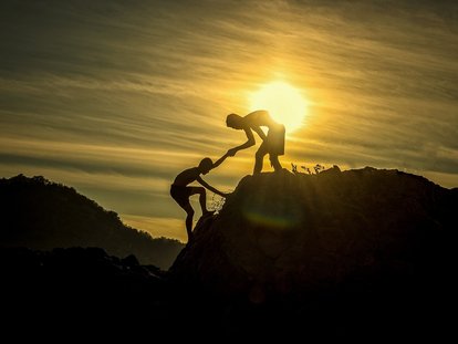 Picture of 2 people climbing a mountain during sunset