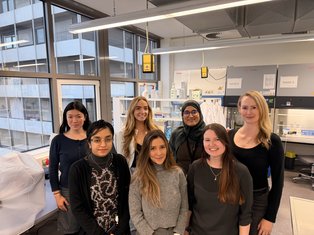 Group photo of the Munir Lab team standing together in a tissue-culture laboratory, smiling toward the camera.