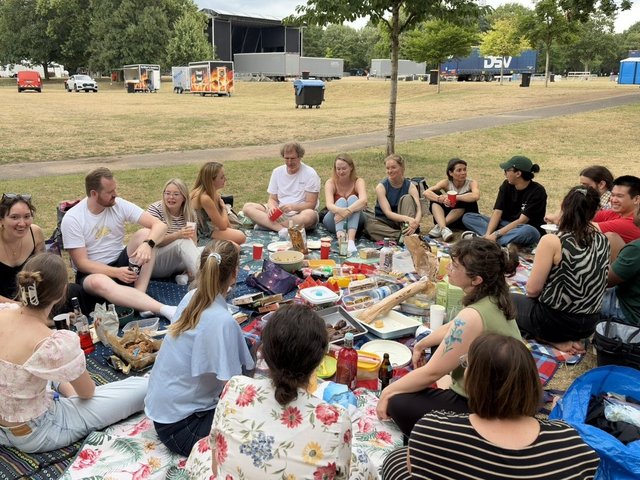 People gathered on picnic blankets for a potluck picnic in a park