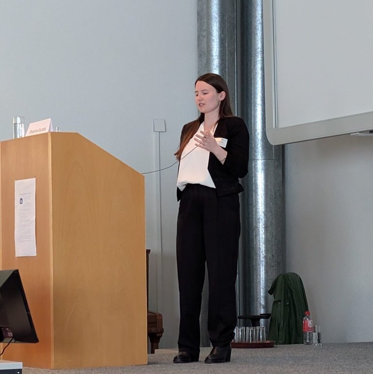 Shanice Gundel presenting on stage during a scientific conference.