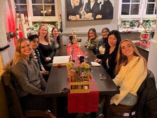Members of the Munir Lab sitting together at a long restaurant table during a festive group dinner, smiling at the camera.