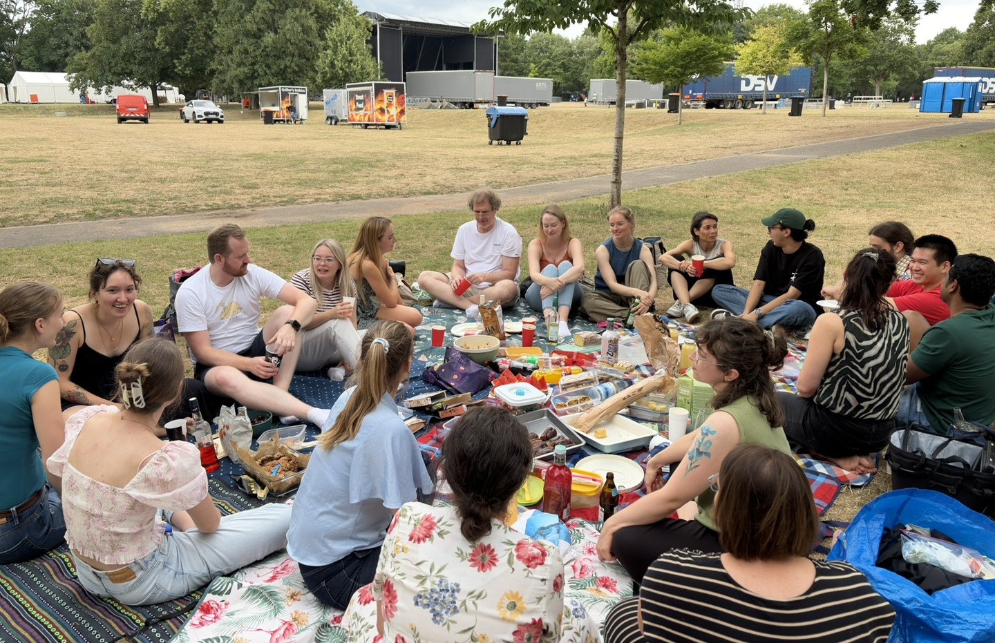 People gathered on picnic blankets for a potluck picnic in a park